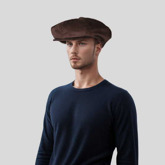 A person wearing a brown corduroy bakerboy cap with a flat brim, styled as vintage headwear.